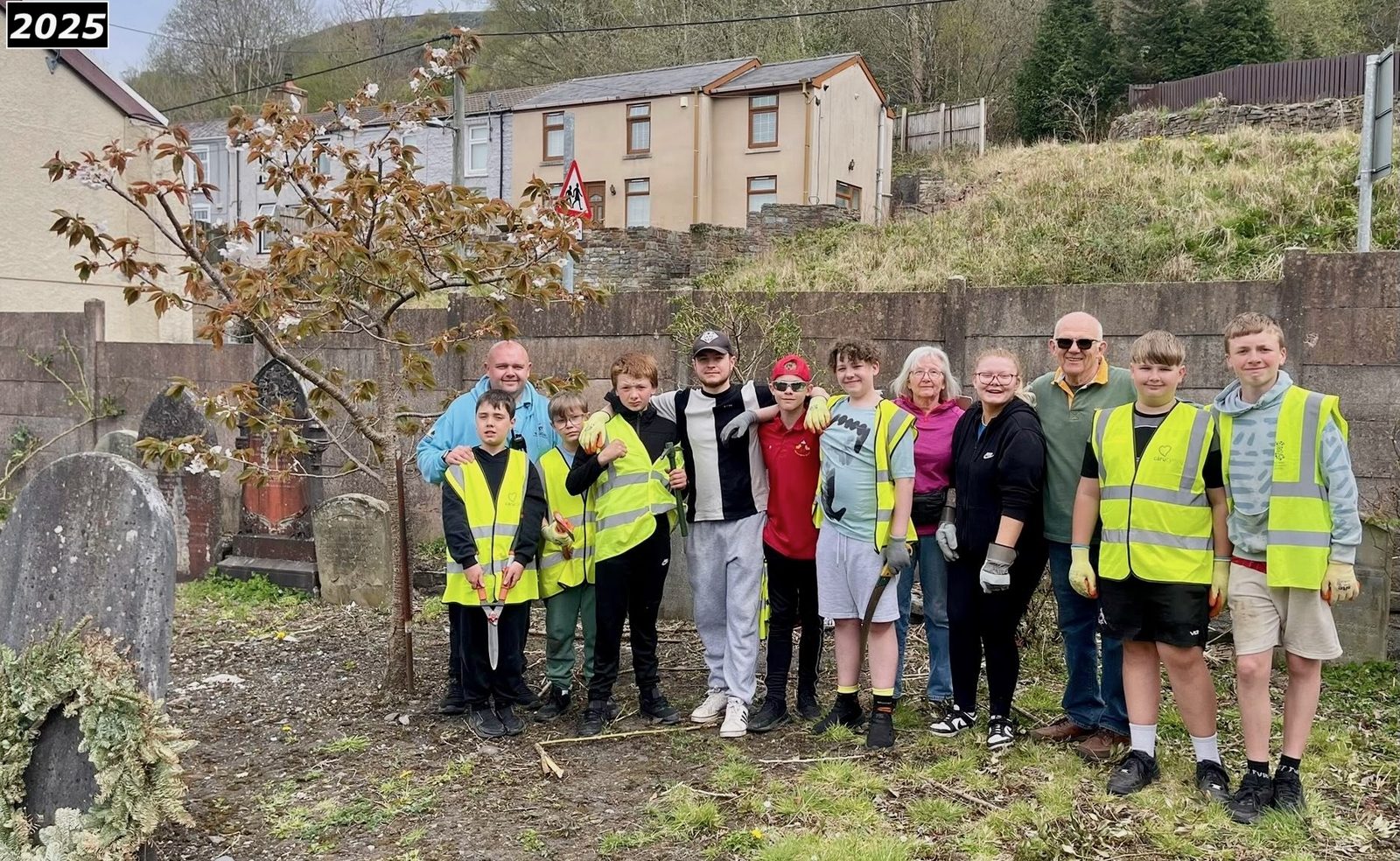 Group of volunteers in hi-vis vests photographed together among the graves at Saron in 2025